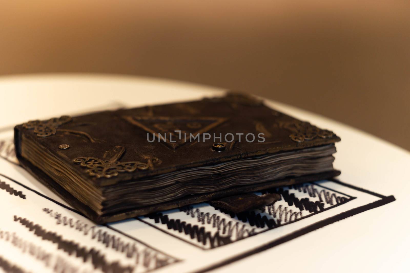 Handmade magic notebook with tower symbol on cover. Leather cover and handmade sheets inside. Very blurred background with soft focus on notebook.