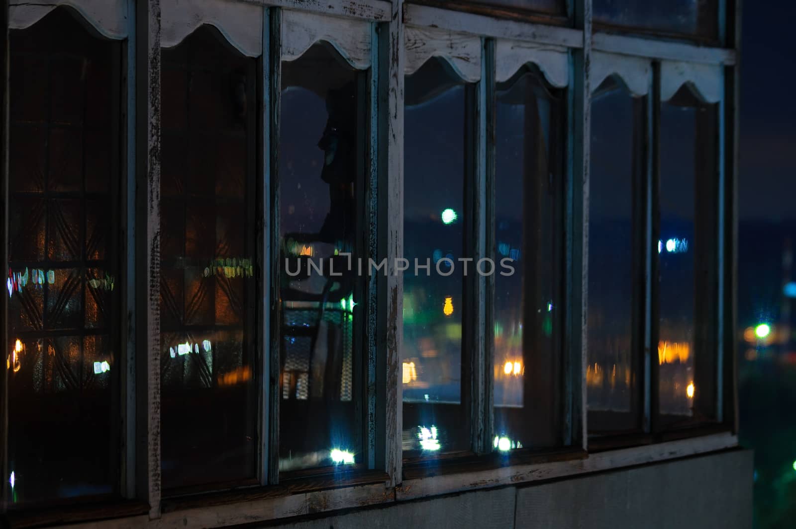 Long exposure cityscape night photo. Balcony with windows let through the lights of the night city.