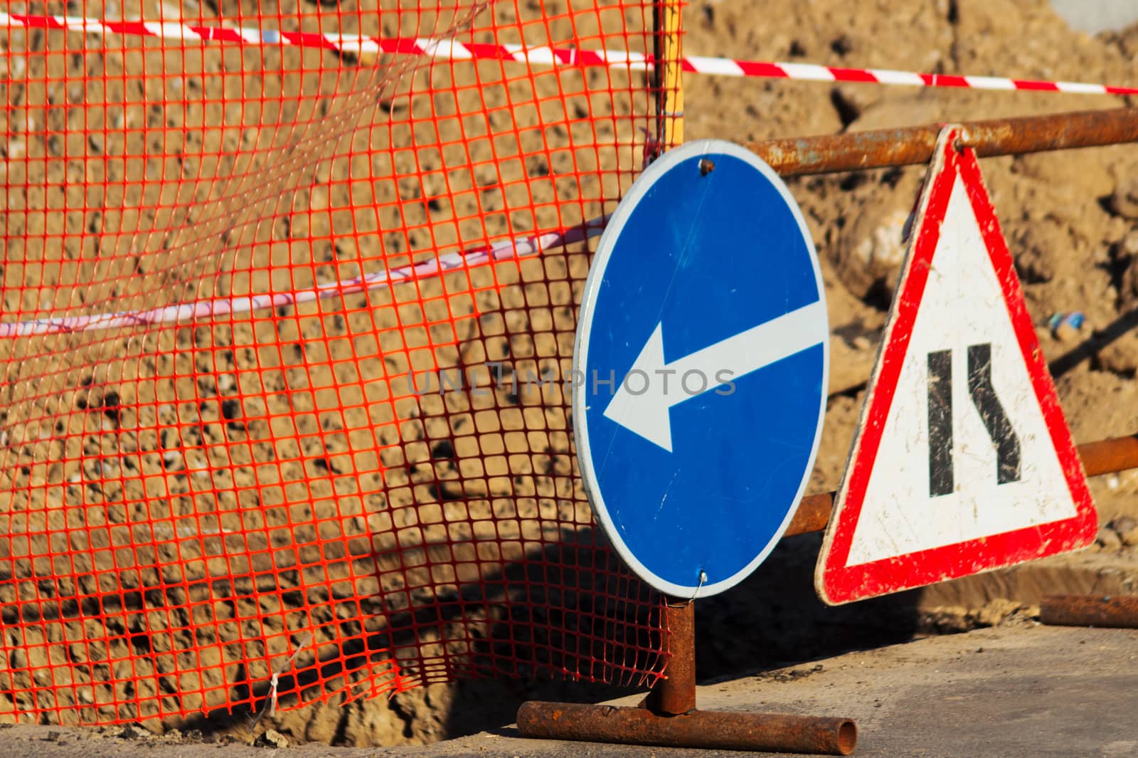 Road atention signs near the trench on the road. Repair work is underway.