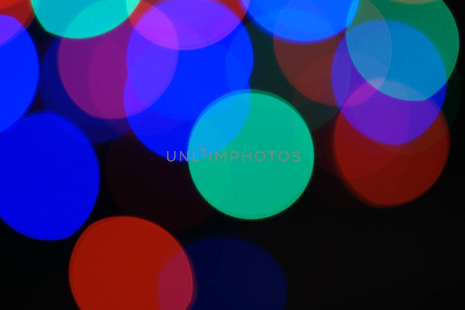 Multi-color blue holiday garland. Garland is blurred. Many very big colorful round lights. Fully defocused photo. Blurred background and foreground. Holiday mood. New Year and Christmas is coming.