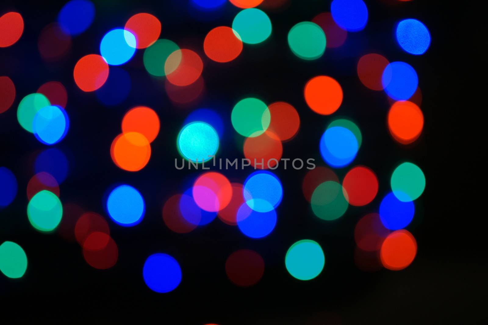 Multi-color blue holiday garland. Garland is blurred. Many big colorful round lights. Fully defocused photo. Blurred background and foreground. Holiday mood. New Year and Christmas is coming.
