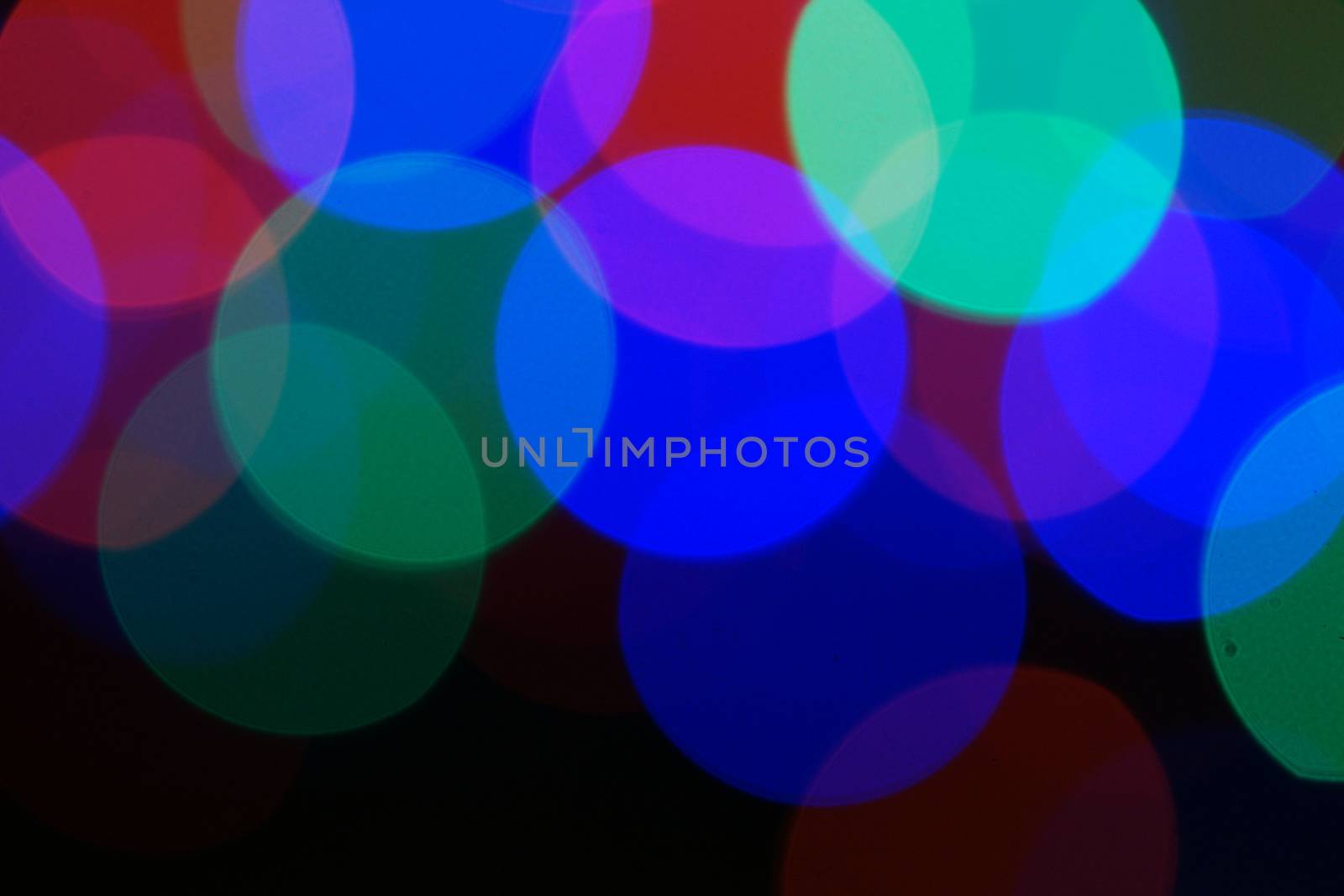 Multi-color blue holiday garland. Garland is blurred. Many very big colorful round lights. Fully defocused photo. Blurred background and foreground. Holiday mood. New Year and Christmas is coming.
