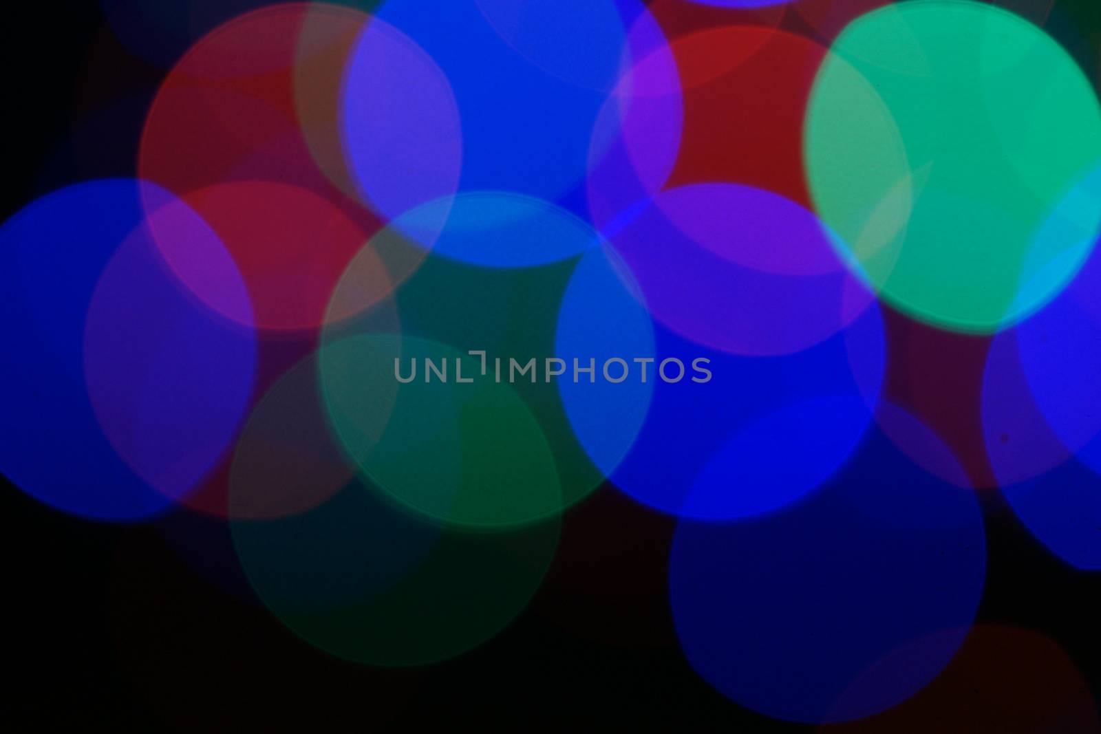 Multi-color blue holiday garland. Garland is blurred. Many very big colorful round lights. Fully defocused photo. Blurred background and foreground. Holiday mood. New Year and Christmas is coming.