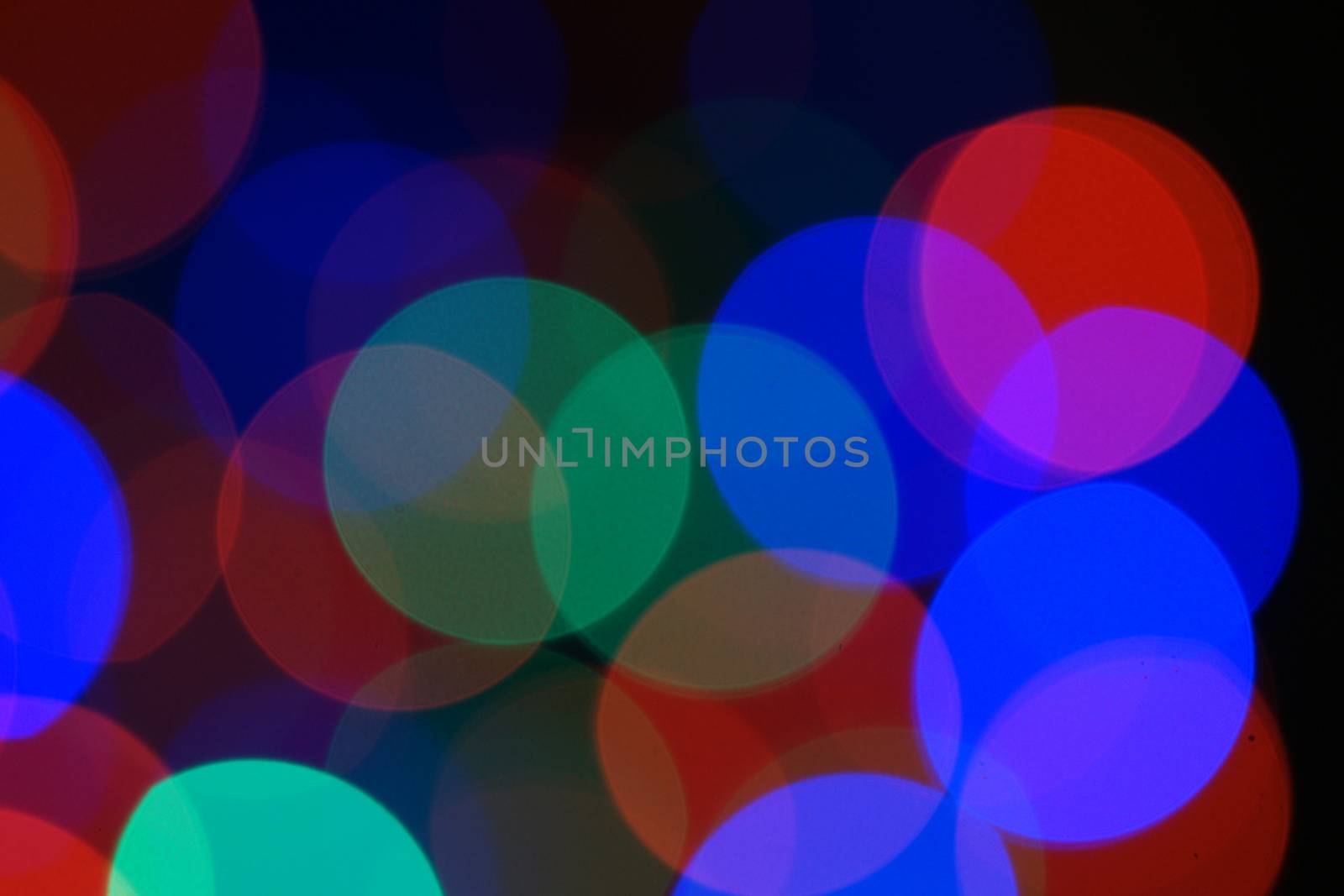 Multi-color blue holiday garland. Garland is blurred. Many very big colorful round lights. Fully defocused photo. Blurred background and foreground. Holiday mood. New Year and Christmas is coming.