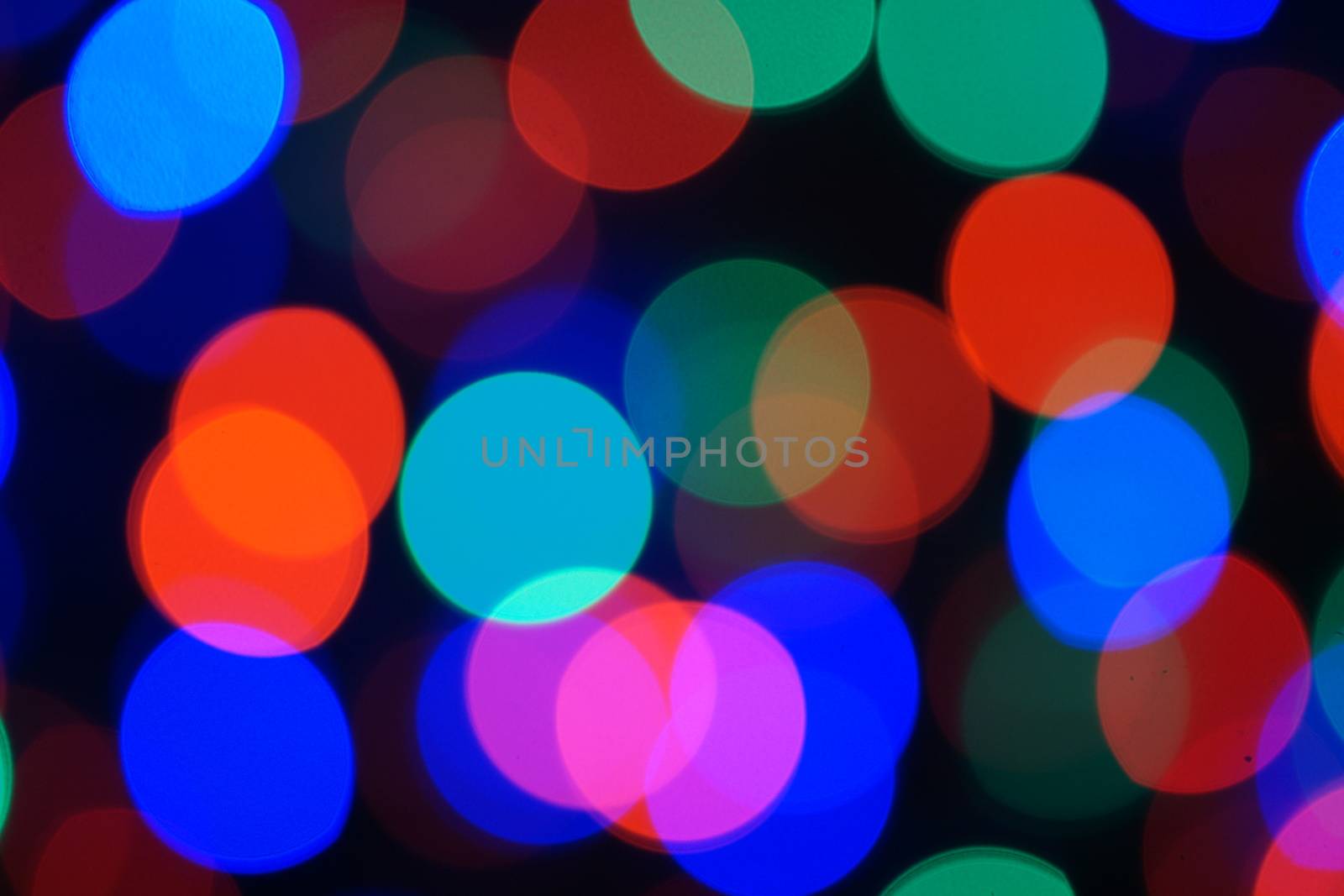 Multi-color blue holiday garland. Garland is blurred. Many big colorful round lights. Fully defocused photo. Blurred background and foreground. Holiday mood. New Year and Christmas is coming.