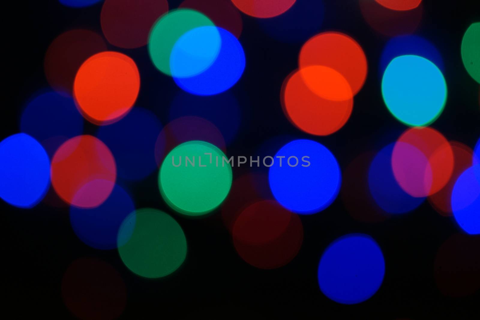 Multi-color blue holiday garland. Garland is blurred. Many big colorful round lights. Fully defocused photo. Blurred background and foreground. Holiday mood. New Year and Christmas is coming.