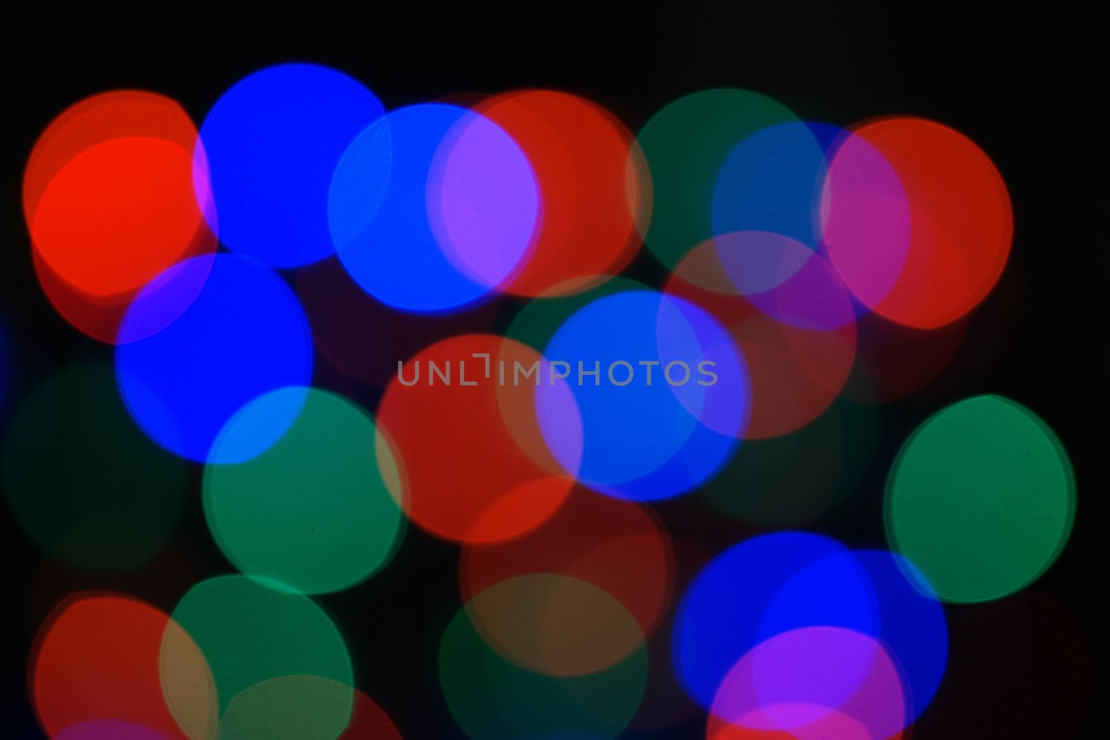 Multi-color blue holiday garland. Garland is blurred. Many big colorful round lights. Fully defocused photo. Blurred background and foreground. Holiday mood. New Year and Christmas is coming.
