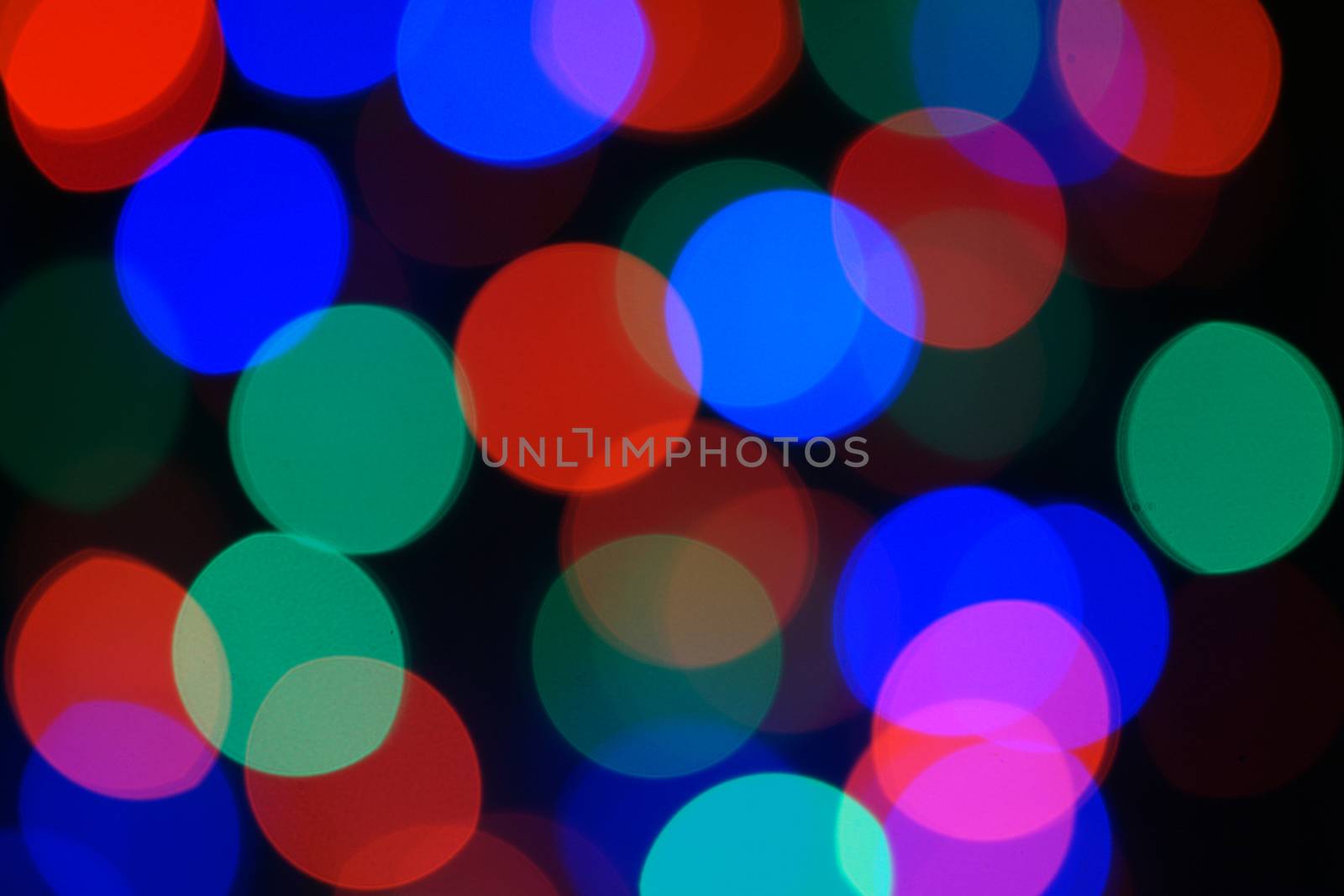 Multi-color blue holiday garland. Garland is blurred. Many big colorful round lights. Fully defocused photo. Blurred background and foreground. Holiday mood. New Year and Christmas is coming.