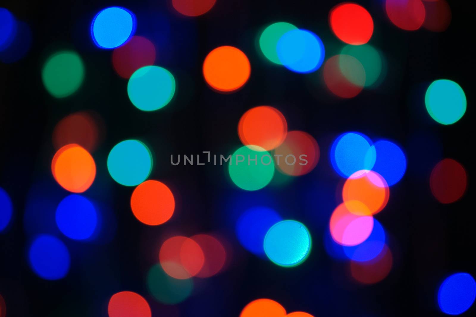 Multi-color blue holiday garland. Garland is blurred. Many big colorful round lights. Fully defocused photo. Blurred background and foreground. Holiday mood. New Year and Christmas is coming.