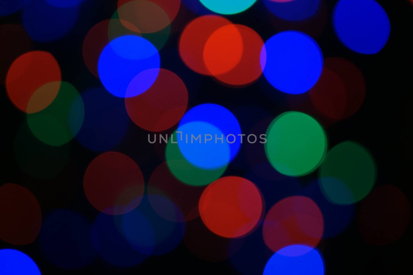 Multi-color blue holiday garland. Garland is blurred. Many big colorful round lights. Fully defocused photo. Blurred background and foreground. Holiday mood. New Year and Christmas is coming.
