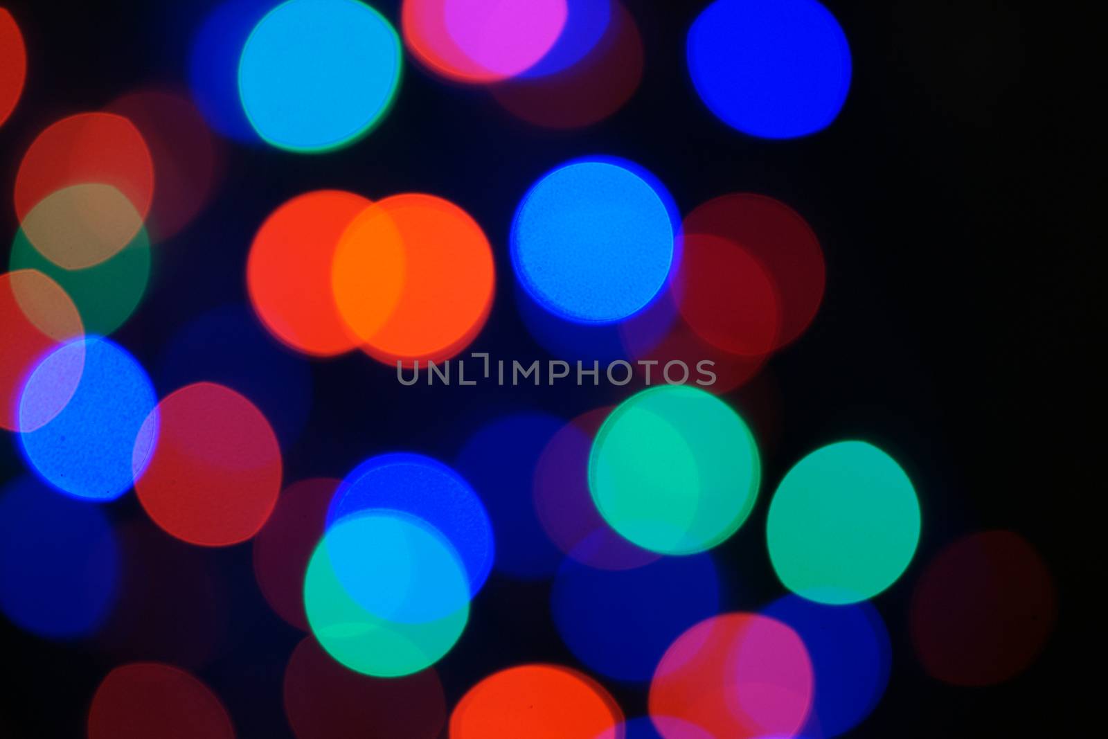 Multi-color blue holiday garland. Garland is blurred. Many big colorful round lights. Fully defocused photo. Blurred background and foreground. Holiday mood. New Year and Christmas is coming.