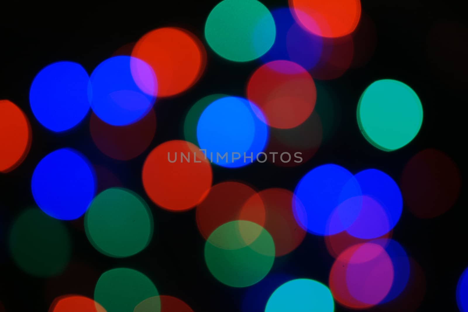 Multi-color blue holiday garland. Garland is blurred. Many big colorful round lights. Fully defocused photo. Blurred background and foreground. Holiday mood. New Year and Christmas is coming.