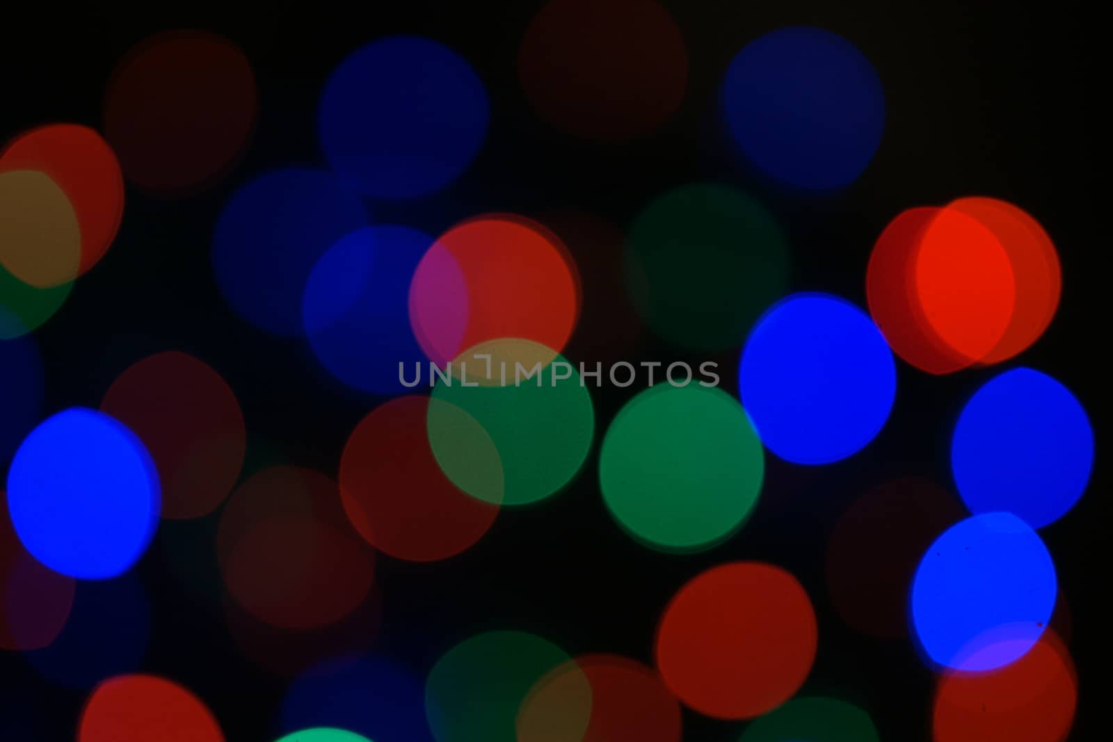 Multi-color blue holiday garland. Garland is blurred. Many big colorful round lights. Fully defocused photo. Blurred background and foreground. Holiday mood. New Year and Christmas is coming.