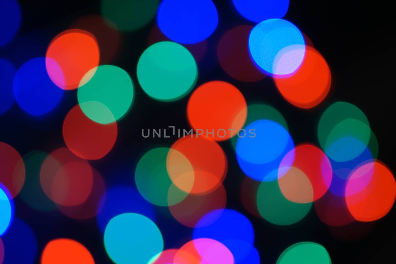 Multi-color blue holiday garland. Garland is blurred. Many big colorful round lights. Fully defocused photo. Blurred background and foreground. Holiday mood. New Year and Christmas is coming.