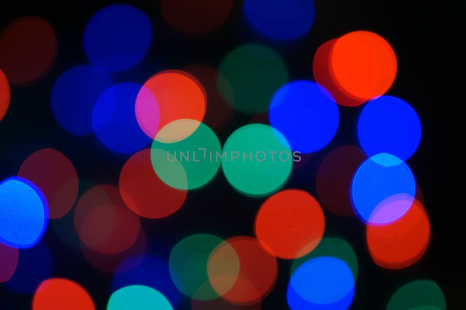 Multi-color blue holiday garland. Garland is blurred. Many big colorful round lights. Fully defocused photo. Blurred background and foreground. Holiday mood. New Year and Christmas is coming.