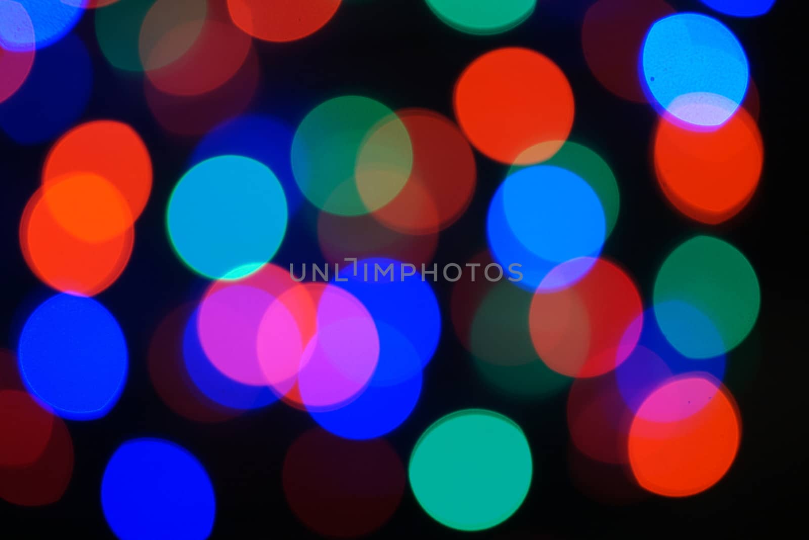 Multi-color blue holiday garland. Garland is blurred. Many big colorful round lights. Fully defocused photo. Blurred background and foreground. Holiday mood. New Year and Christmas is coming.
