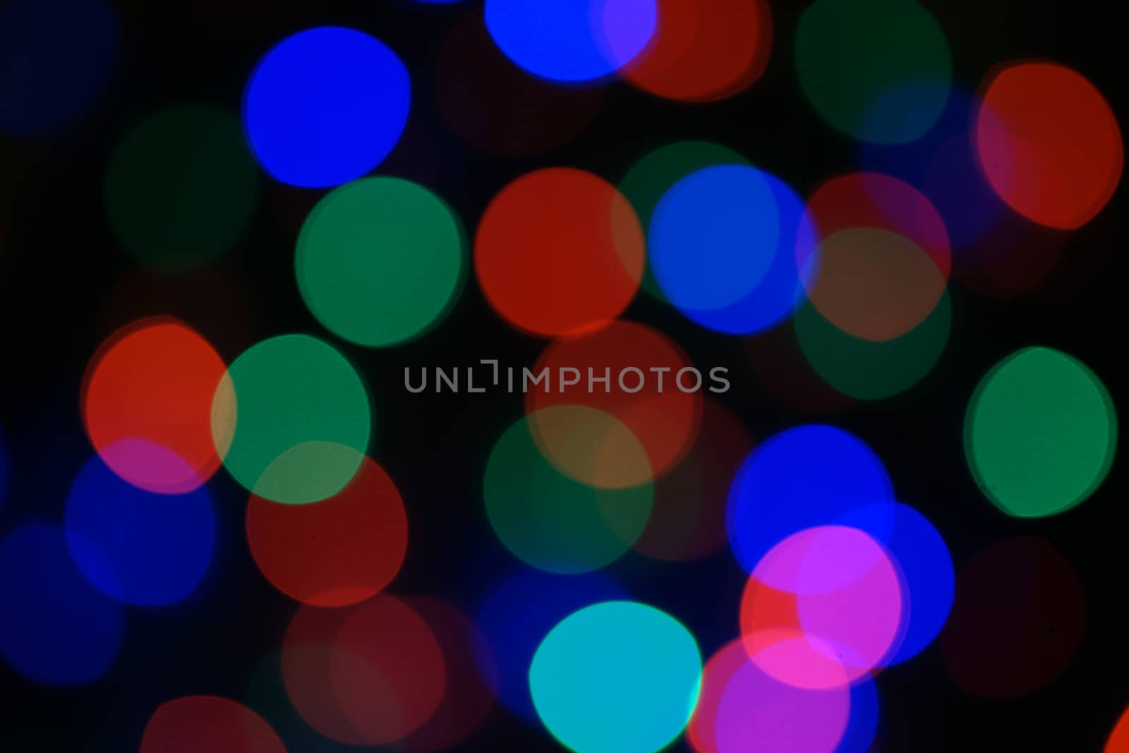 Multi-color blue holiday garland. Garland is blurred. Many big colorful round lights. Fully defocused photo. Blurred background and foreground. Holiday mood. New Year and Christmas is coming.