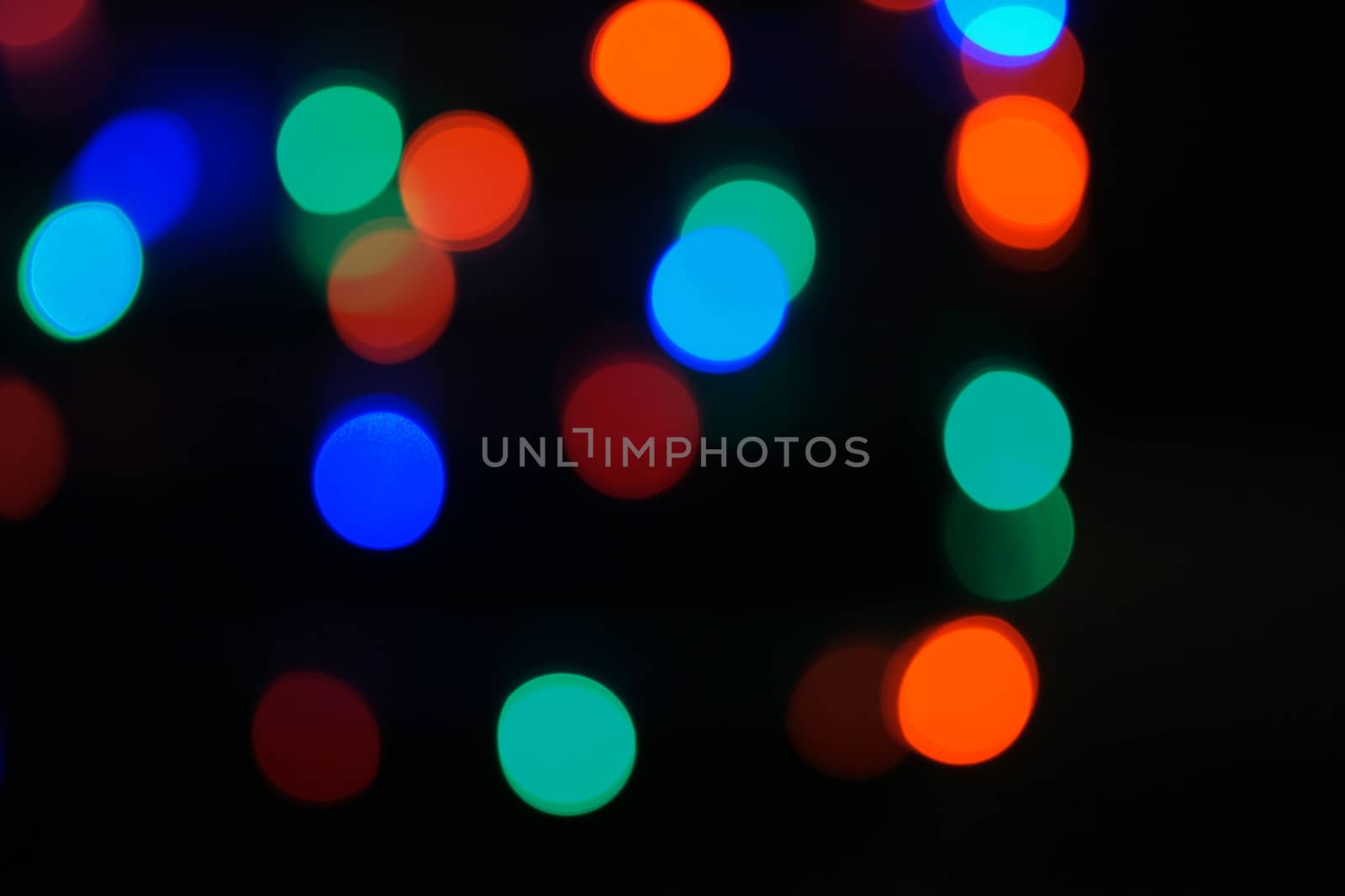 Multi-color blue holiday garland. Garland is blurred. Many big colorful round lights. Fully defocused photo. Blurred background and foreground. Holiday mood. New Year and Christmas is coming.