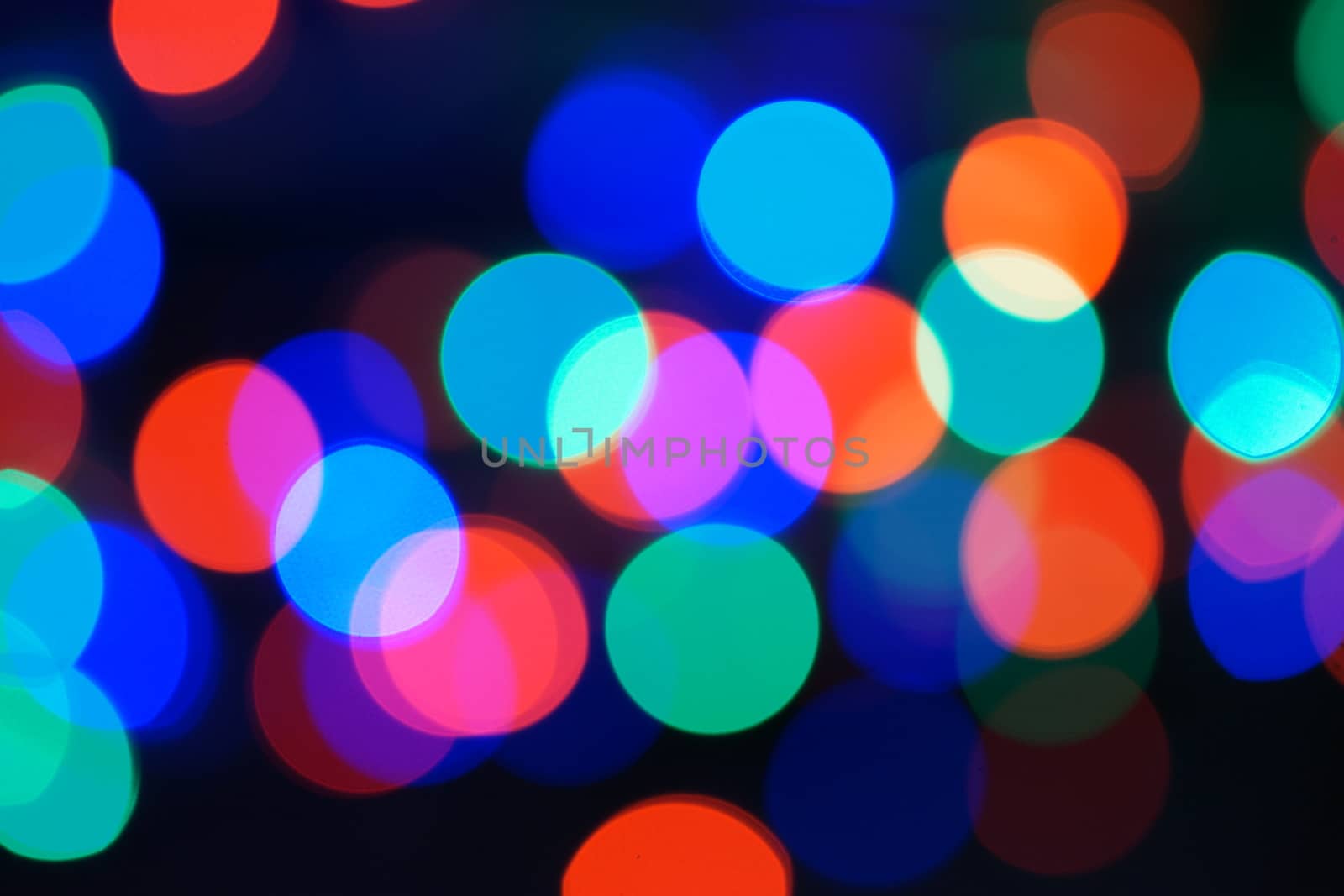 Multi-color blue holiday garland. Garland is blurred. Many big colorful round lights. Fully defocused photo. Blurred background and foreground. Holiday mood. New Year and Christmas is coming.