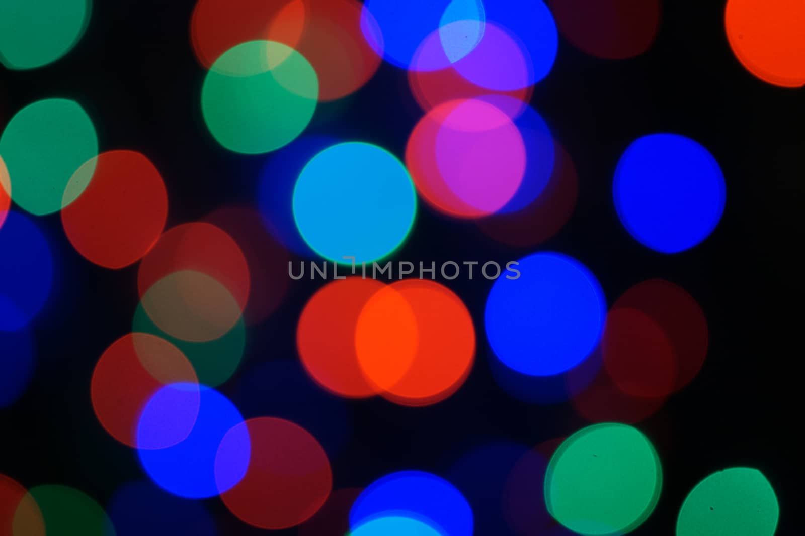 Multi-color blue holiday garland. Garland is blurred. Many big colorful round lights. Fully defocused photo. Blurred background and foreground. Holiday mood. New Year and Christmas is coming.