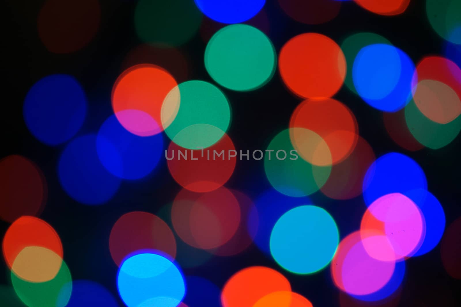 Multi-color blue holiday garland. Garland is blurred. Many big colorful round lights. Fully defocused photo. Blurred background and foreground. Holiday mood. New Year and Christmas is coming.