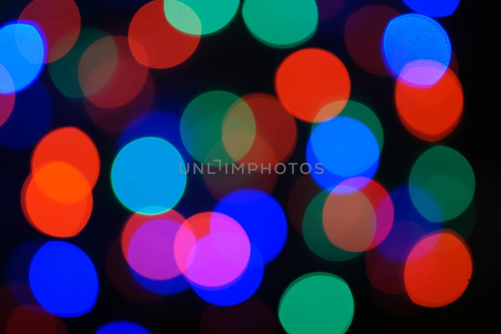 Multi-color blue holiday garland. Garland is blurred. Many big colorful round lights. Fully defocused photo. Blurred background and foreground. Holiday mood. New Year and Christmas is coming.