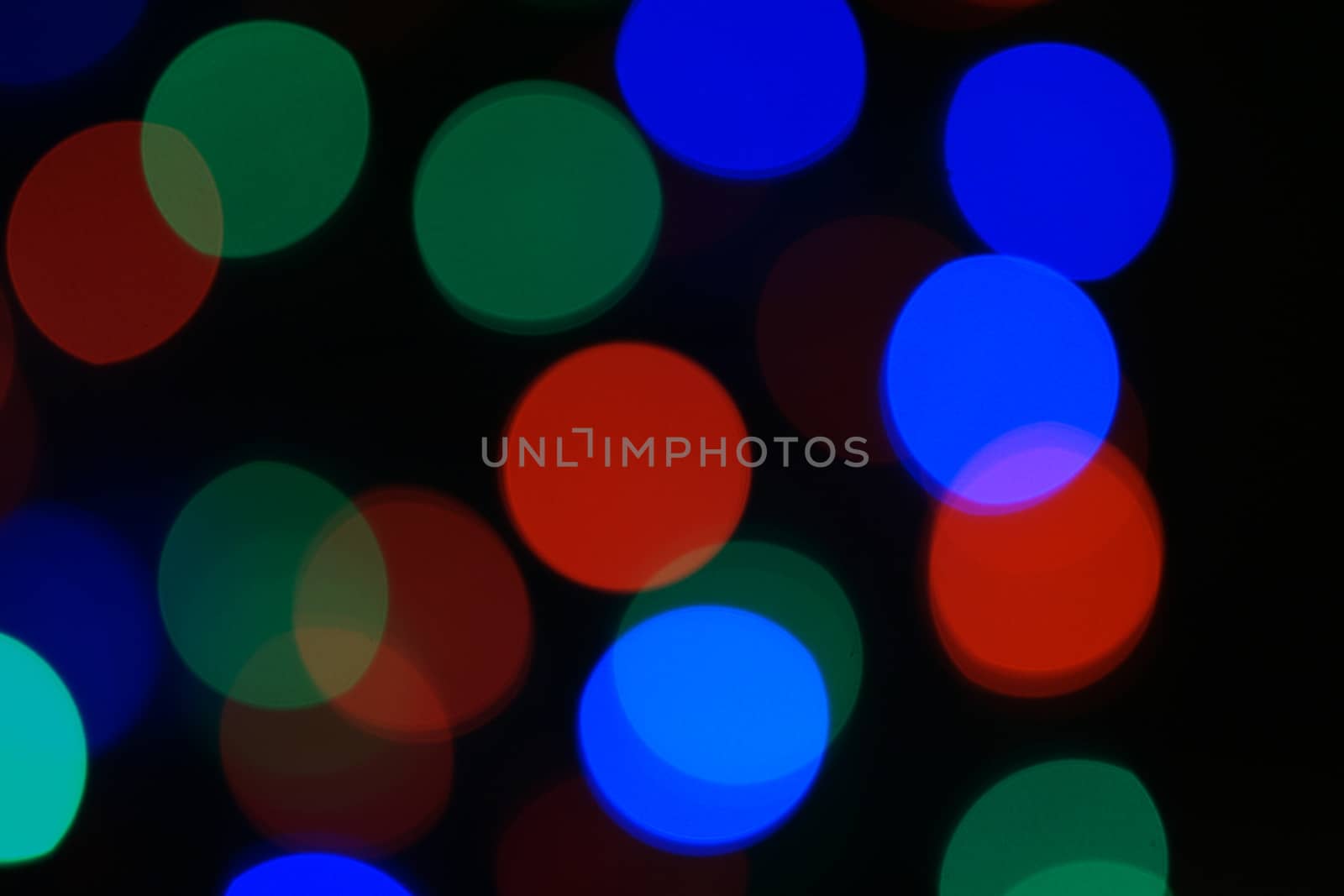 Multi-color blue holiday garland. Garland is blurred. Many big colorful round lights. Fully defocused photo. Blurred background and foreground. Holiday mood. New Year and Christmas is coming.
