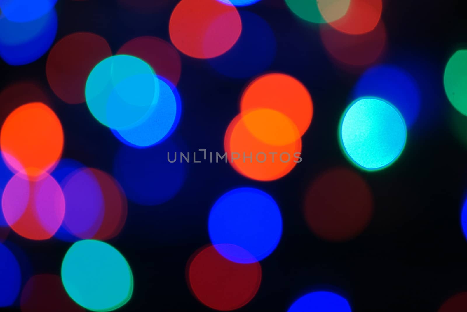 Multi-color blue holiday garland. Garland is blurred. Many big colorful round lights. Fully defocused photo. Blurred background and foreground. Holiday mood. New Year and Christmas is coming.