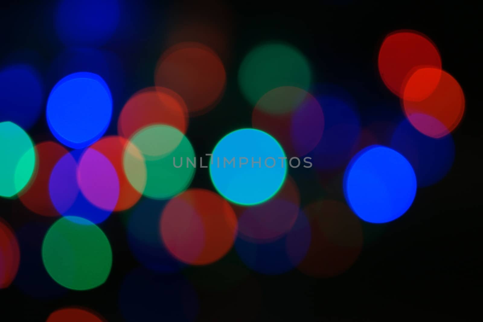 Multi-color blue holiday garland. Garland is blurred. Many big colorful round lights. Fully defocused photo. Blurred background and foreground. Holiday mood. New Year and Christmas is coming.