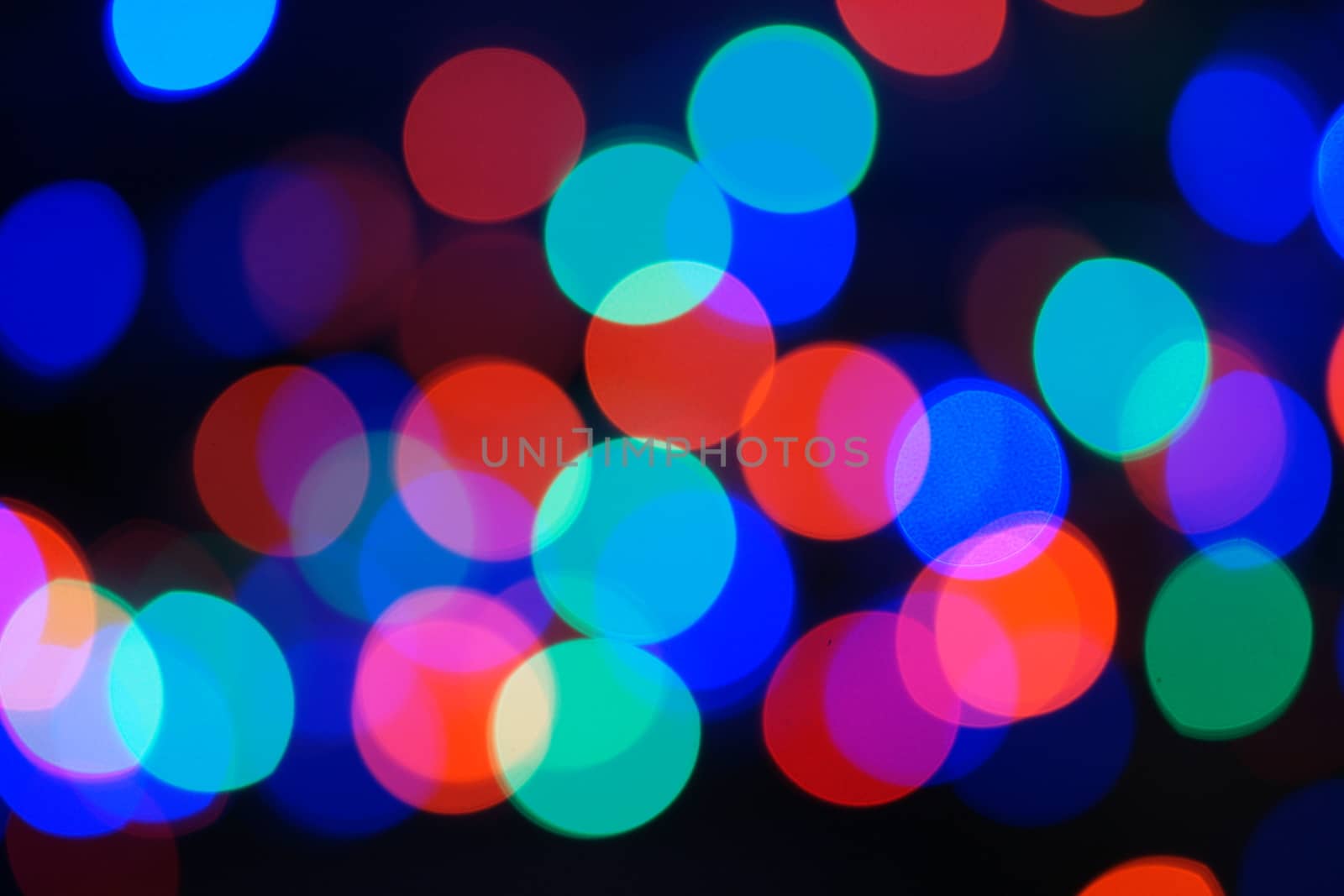 Multi-color blue holiday garland. Garland is blurred. Many big colorful round lights. Fully defocused photo. Blurred background and foreground. Holiday mood. New Year and Christmas is coming.