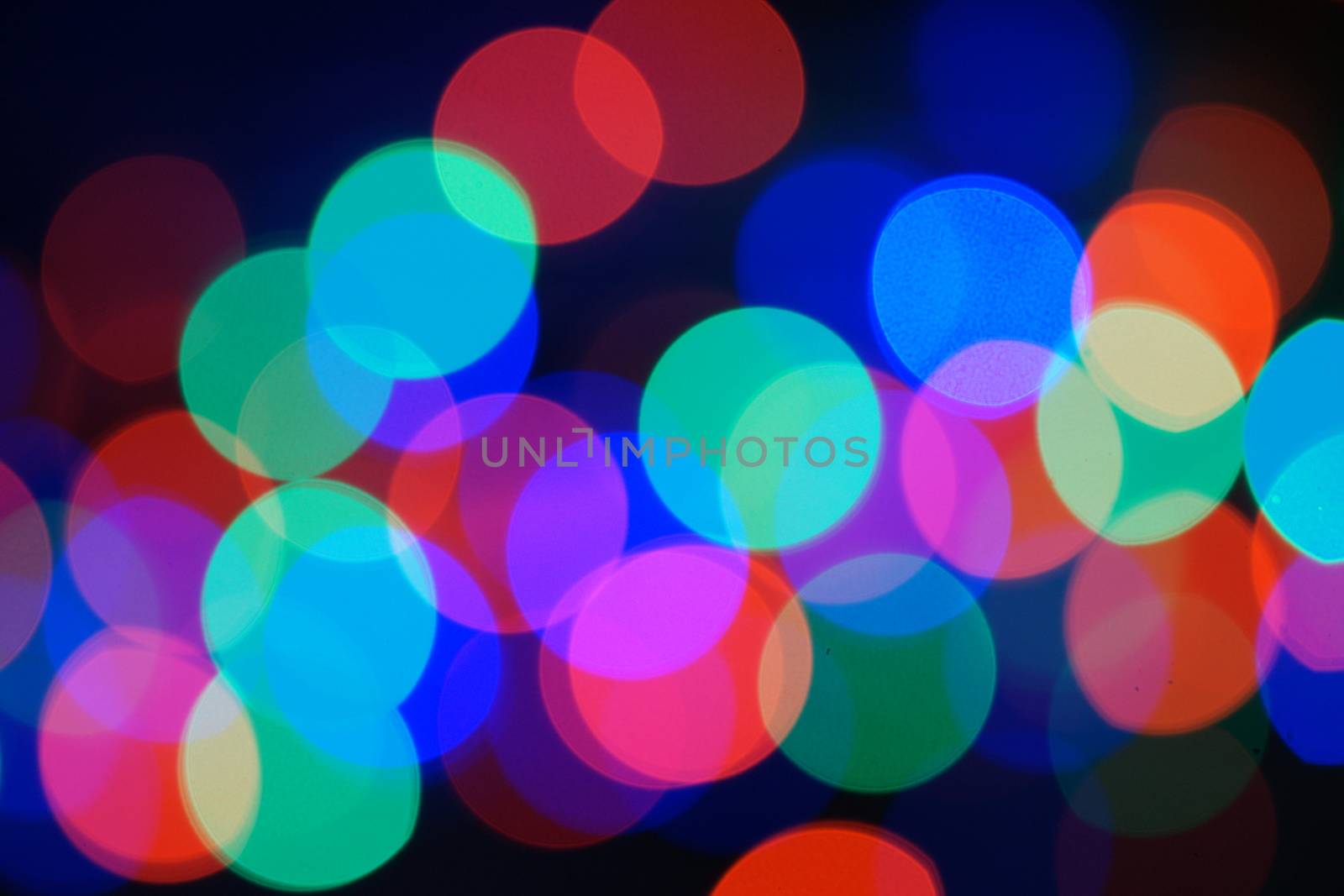 Multi-color blue holiday garland. Garland is blurred. Many big colorful round lights. Fully defocused photo. Blurred background and foreground. Holiday mood. New Year and Christmas is coming.