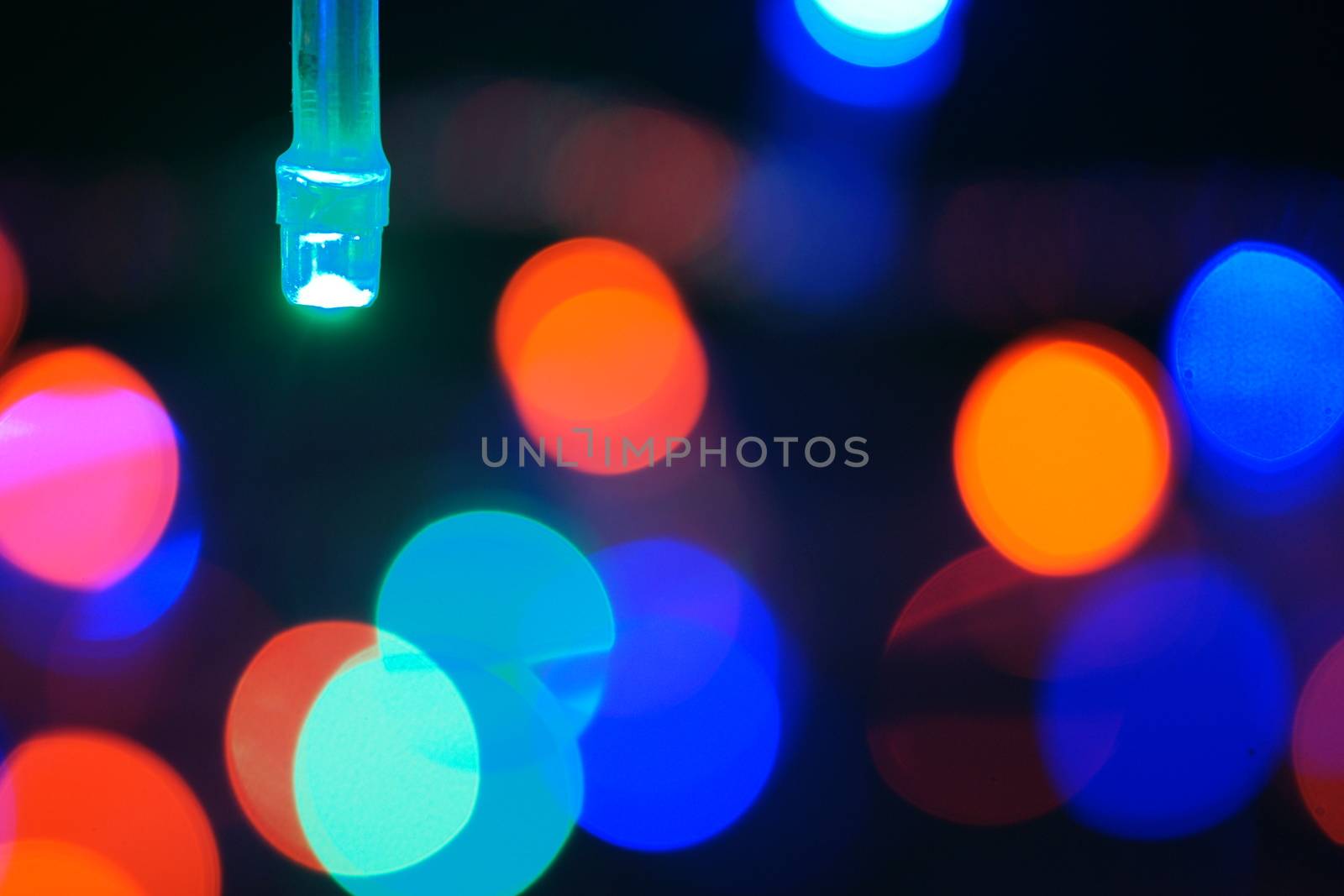 Multi-color blue holiday garland. Garland is blurred. Many big colorful round lights. Fully defocused photo. Blurred background and foreground. Holiday mood. New Year and Christmas is coming.