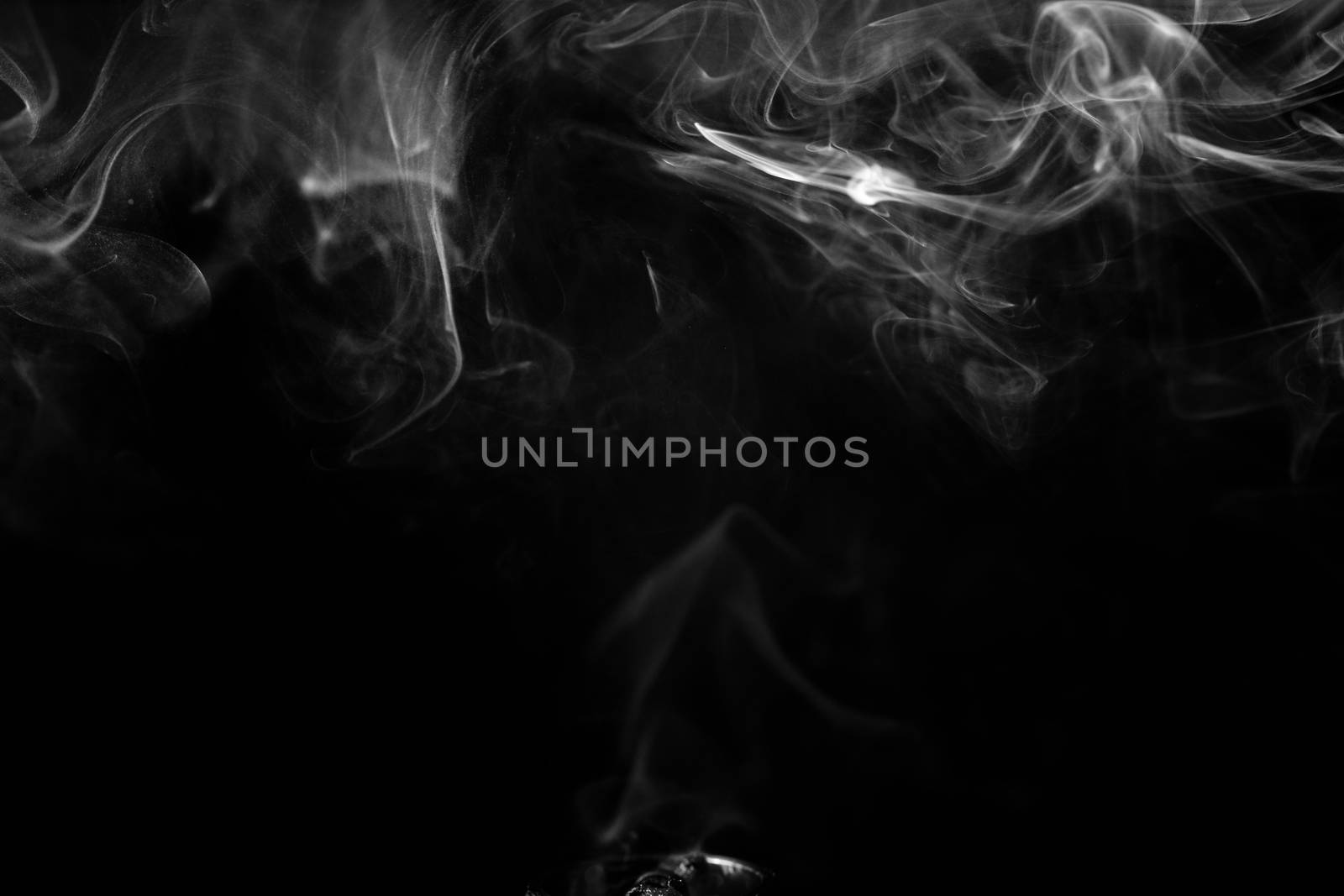 Vape smoke clouds isolated on black background. Hot vape liquid splash in vape coil. Nice aromatic cloud. Low light black and white monochrome photo. Underexposed photo in a low key style.