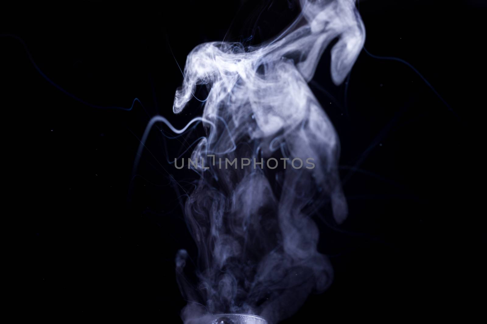 Vape smoke clouds isolated on black background. Hot vape liquid splash in vape coil. Nice aromatic cloud. Low light photo. Underexposed photo in a low key style.