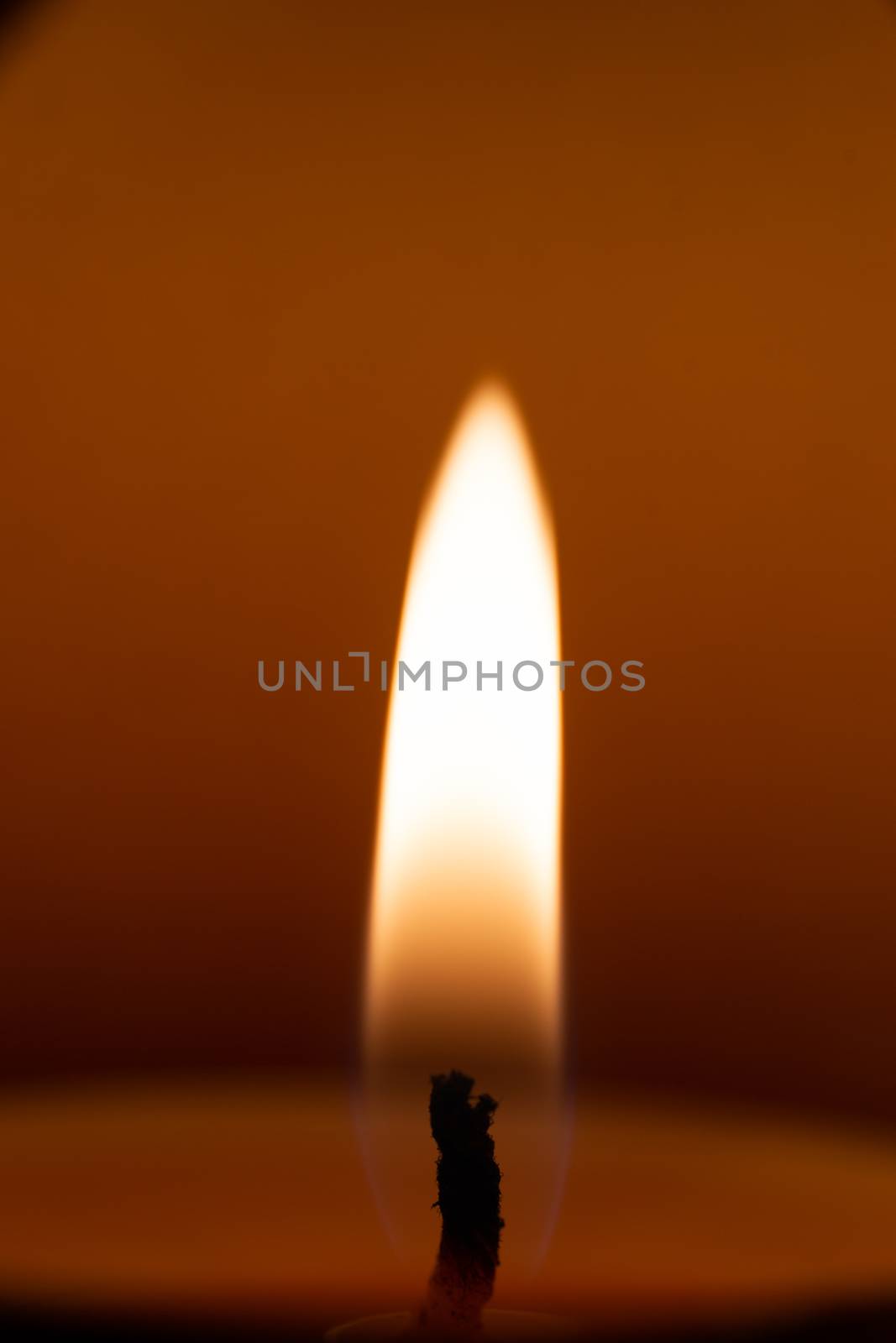 Underexposed low light photo of candle in aromatic lamp. Close-up view