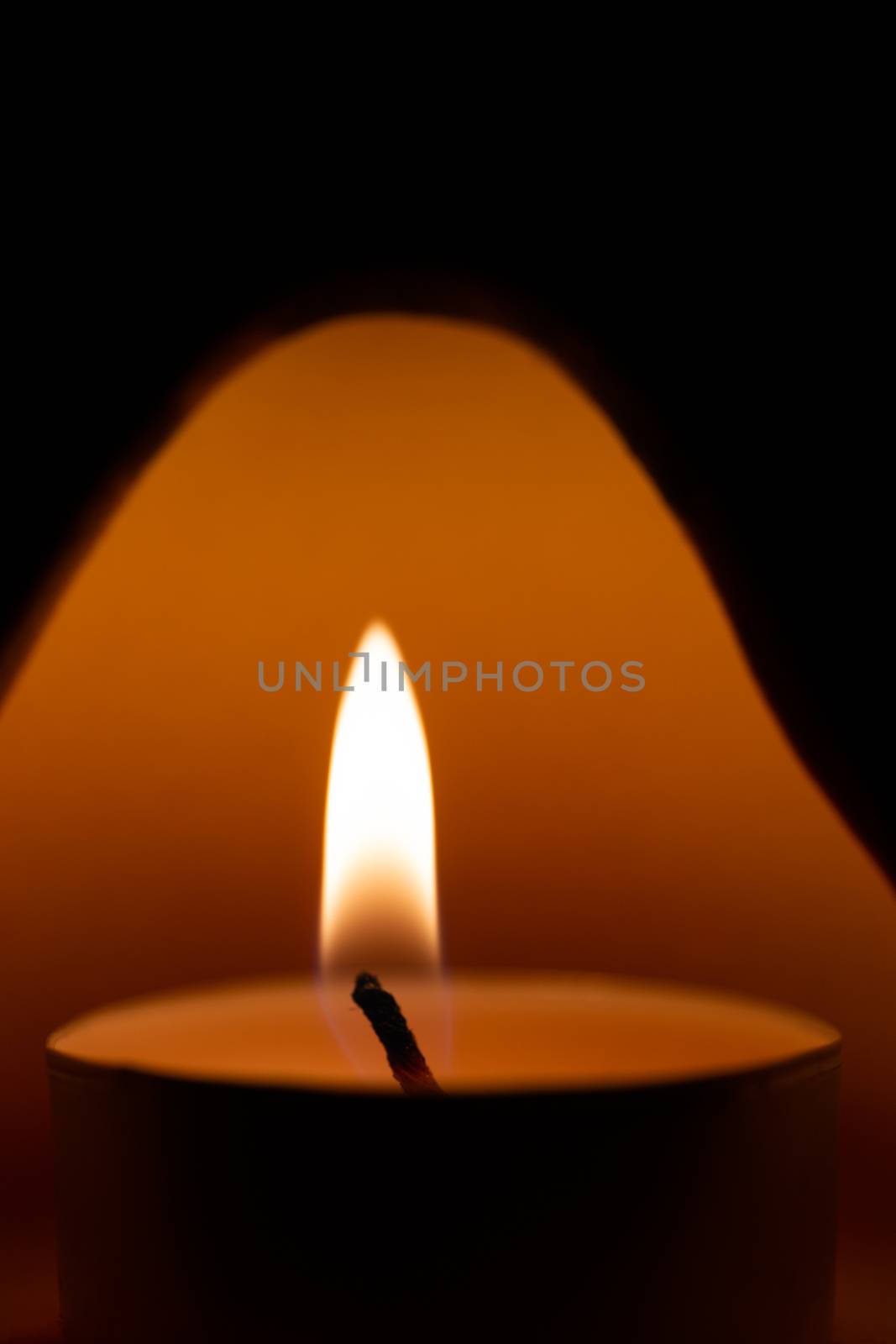 Underexposed low light photo of candle in aromatic lamp. Close-up view