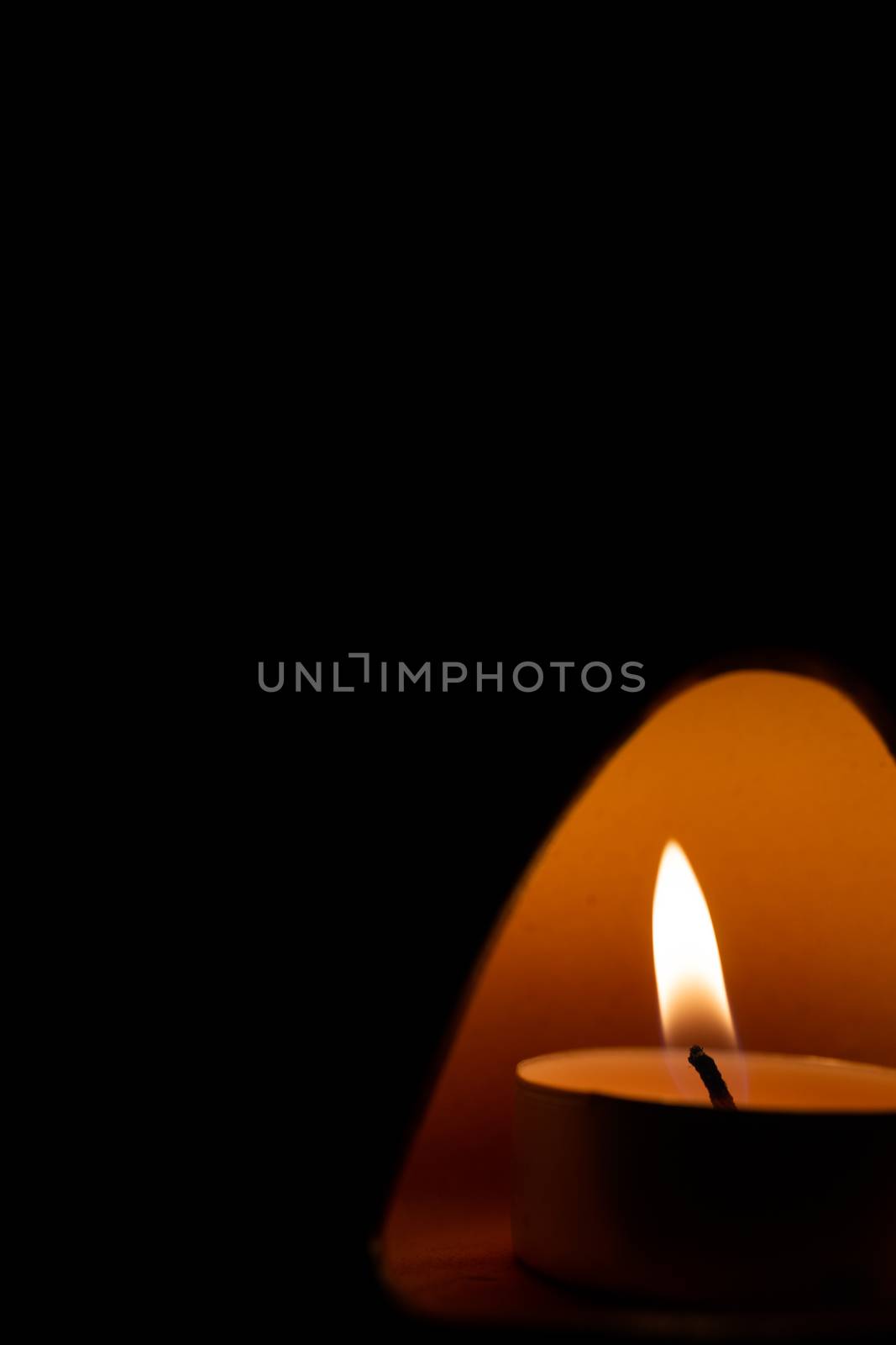 Underexposed low light photo of candle in aromatic lamp. Close-up view