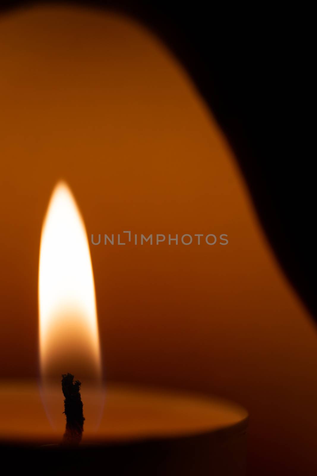 Underexposed low light photo of candle in aromatic lamp. Close-up view