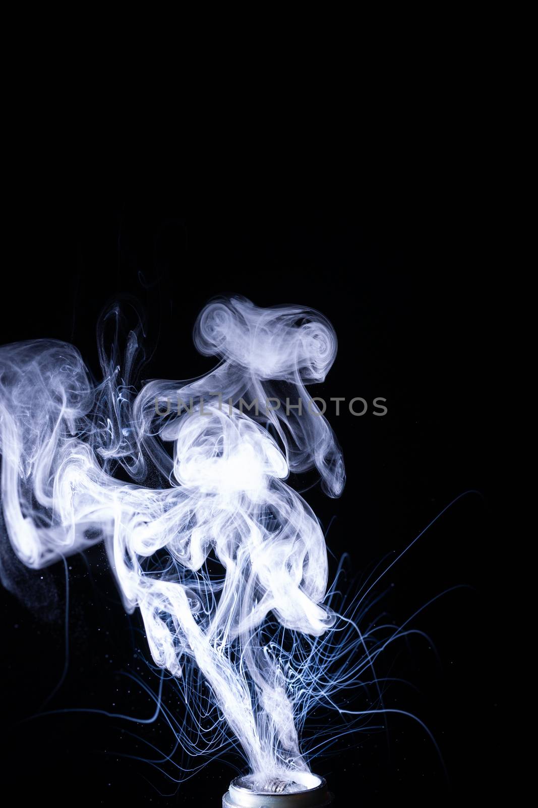 Vape smoke clouds isolated on black background. Hot vape liquid splash in vape coil. Nice aromatic cloud. Low light photo. Underexposed photo in a low key style.