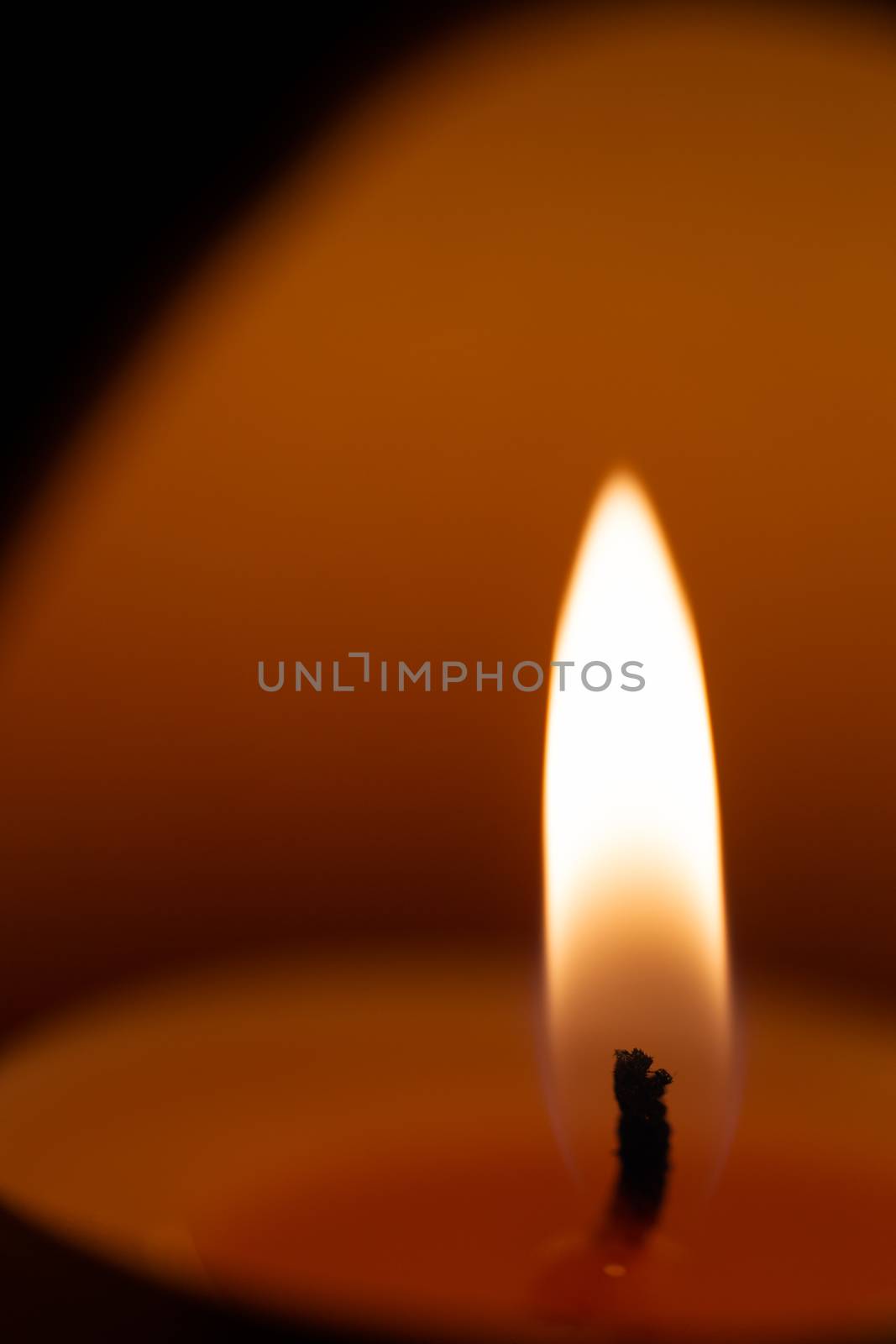 Underexposed low light photo of candle in aromatic lamp. Close-up view