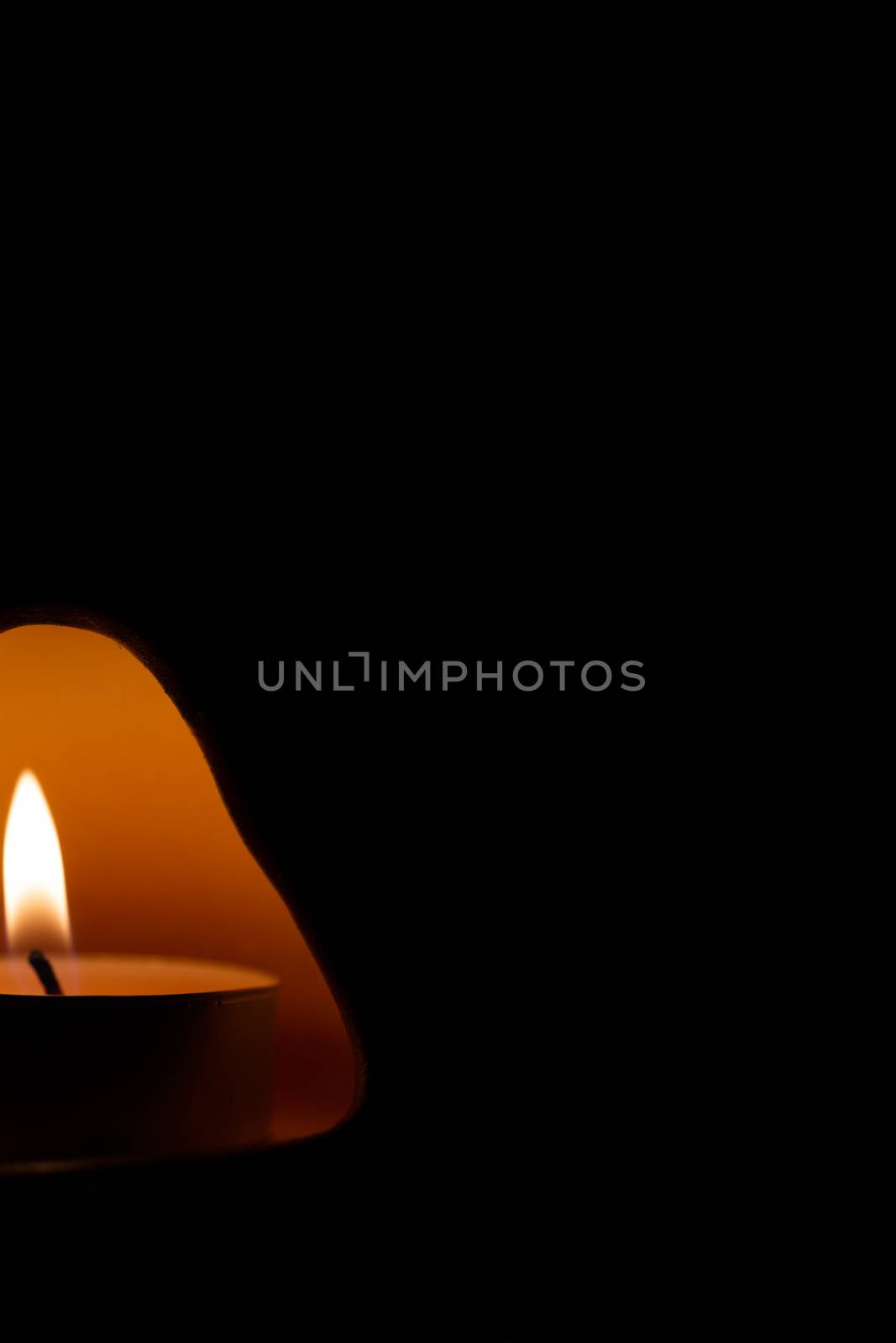Underexposed low light photo of candle in aromatic lamp. Close-up view