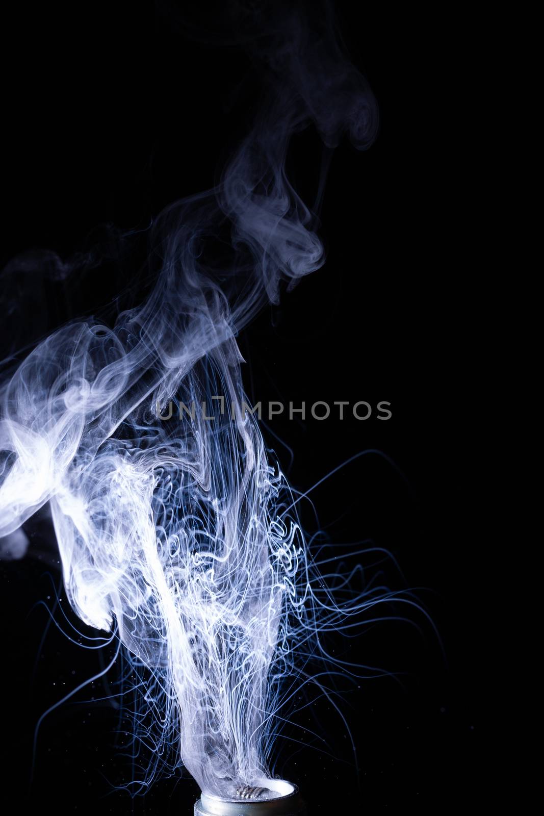 Vape smoke clouds isolated on black background. Hot vape liquid splash in vape coil. Nice aromatic cloud. Low light photo. Underexposed photo in a low key style.