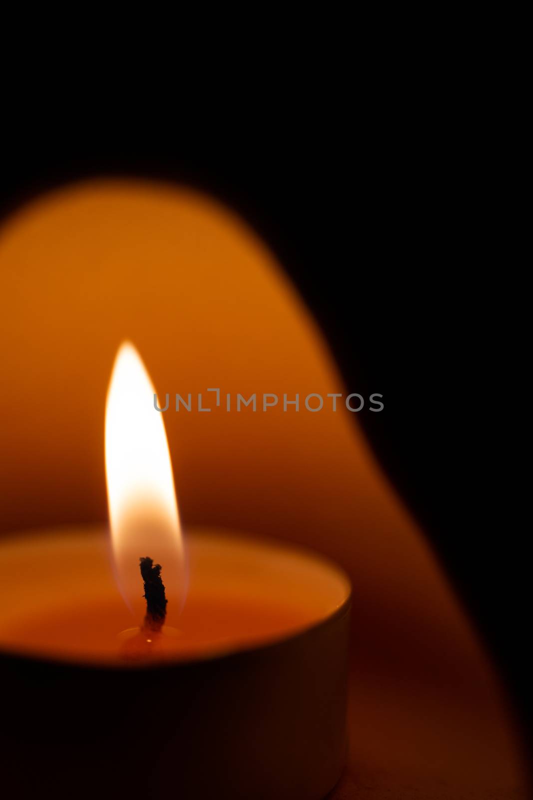 Underexposed low light photo of candle in aromatic lamp. Close-up view