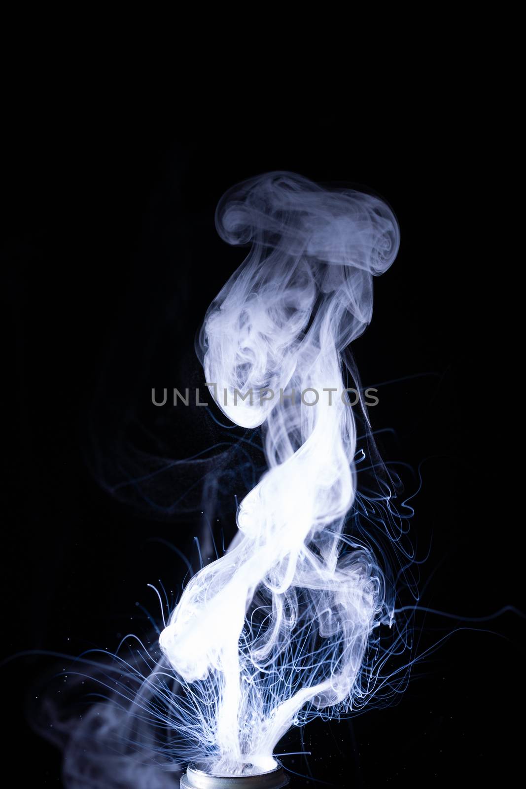 Vape smoke clouds isolated on black background. Hot vape liquid splash in vape coil. Nice aromatic cloud. Low light photo. Underexposed photo in a low key style.