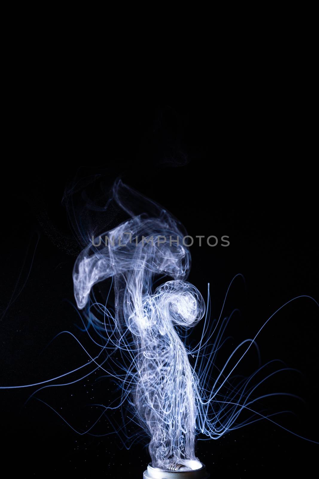 Vape smoke clouds isolated on black background. Hot vape liquid splash in vape coil. Nice aromatic cloud. Low light photo. Underexposed photo in a low key style.