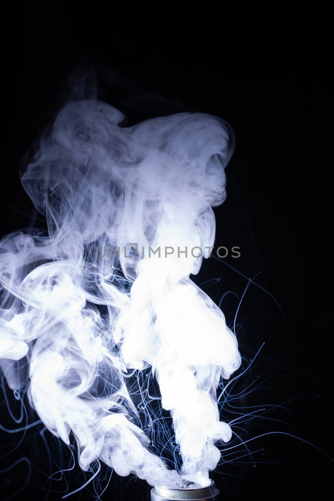 Vape smoke clouds isolated on black background. Hot vape liquid splash in vape coil. Nice aromatic cloud. Low light photo. Underexposed photo in a low key style.