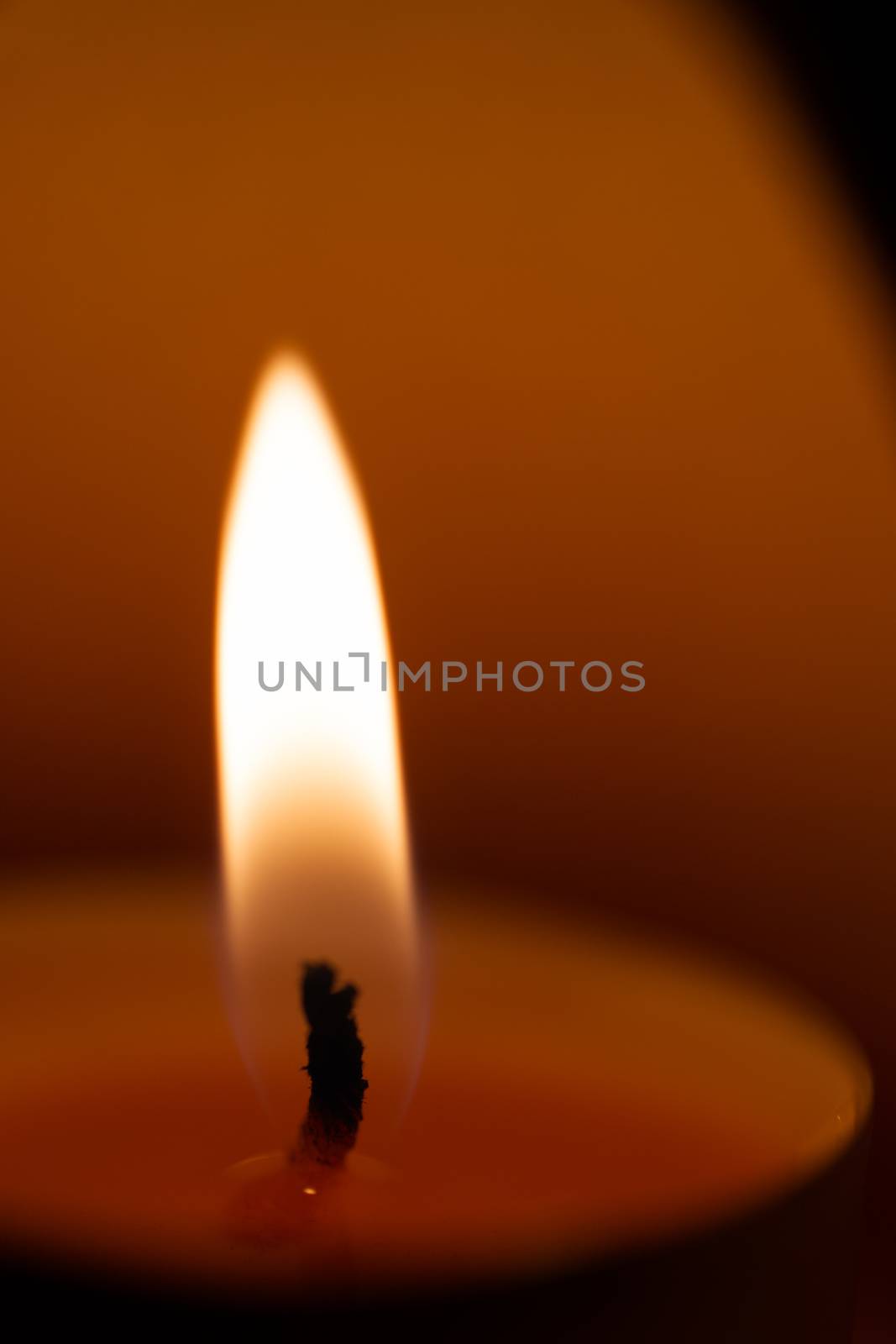 Underexposed low light photo of candle in aromatic lamp. Close-up view