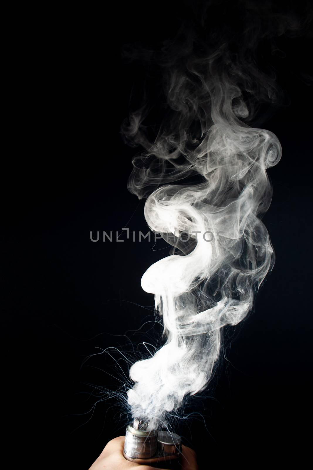 Male hand holds vape without atomiser. Column of vape clouds splash from coil on black background. Fog is white. Stock isolated white smoke with spray boiling glycerine.