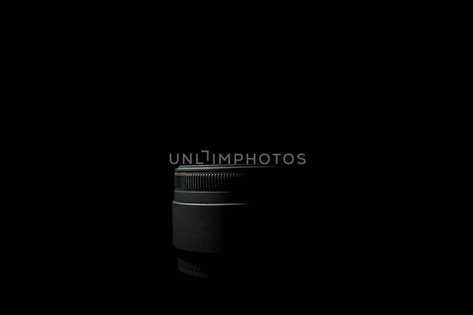Underexposed photo of DSLR camera lens lying on black background. Stock photo isolated. Low light photo and large depth of field.