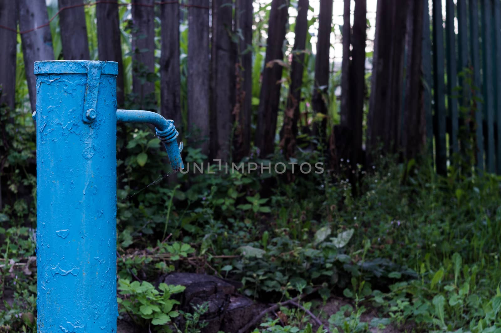 The blue broken water hydrant. Paint is very old and cracked.